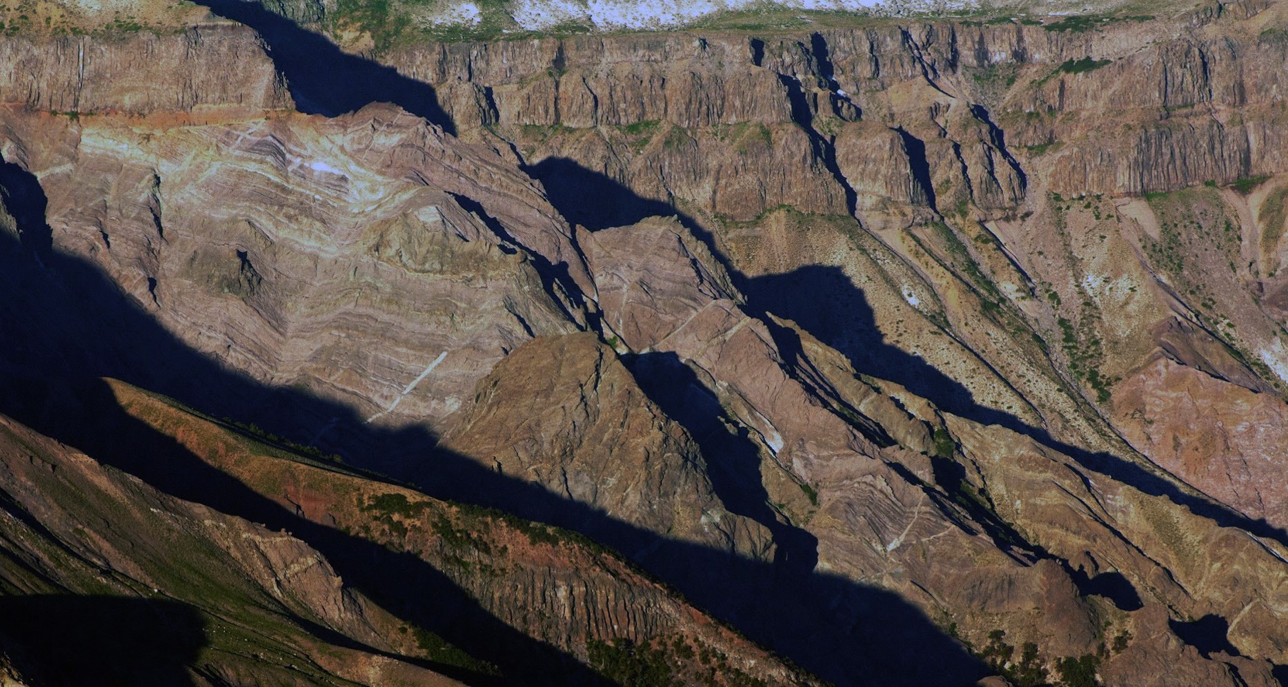 Fotografía tomada en el sector del Enladrillado disponible en Google Earth (Verónica Hernández-Montañas). Se observa la superficie de contacto entre el grupo de las rocas antiguas (abajo, de apariencia rayada) y el grupo de rocas más jóvenes (arriba, estratos gruesos hasta el techo)